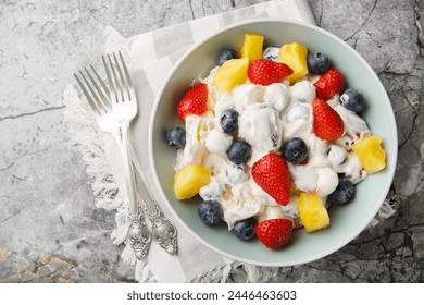 Cream cheese salad with strawberries, blueberries, pineapple close-up in a bowl on a marble table. Horizontal top view from above
 - Powered by Shutterstock