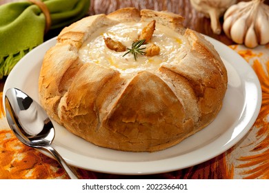 Cream cheese soup inside Italian bread on decorated table.