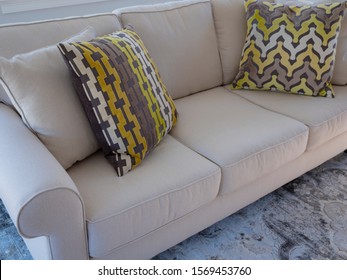 Cream Colored Couch With Geometric Patterned Throw Pillows