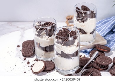 Cream and cookie layered dessert. Homemade oreo trifle, vanilla chocolate cookie layered cheese cake in glass, variation of traditional american breakfast dessert