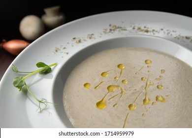 Cream of porcini mushroom soup with truffle oil on a white plate