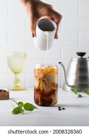 Cream Is Poured Into Cold Black Coffee With Ice Cubes. Coldbrew. Summer Drinks.