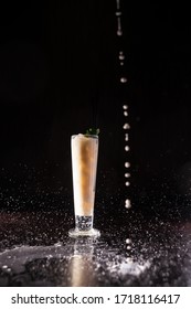 cream pouring around a cocktail; spray flying in different directions; cocktail isolated on black background