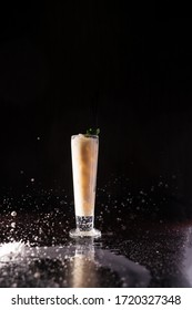 cream pouring around a cocktail; spray flying in different directions; cocktail isolated on black background