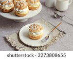 Cream puffs filled with vanilla cream and whipped cream on a white plate