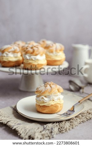 Cream puffs filled with vanilla cream and whipped cream on a white plate