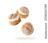 Cream puffs, pastry from choux filled cream covered sugar powder closeup falling flying isolated on white background. Sweet french dessert Choux for coffee break or party.