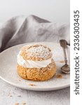 Cream puffs, semla, pastry from choux covered sugar powder on white plate over stone table background. Sweet dessert with chantilly cream for coffee break or party.