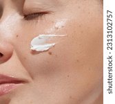 Cream smear. Beauty close up portrait of young woman with a healthy skin is applying a facial skincare product. Face  daily care routine 
