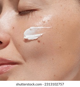 Cream smear. Beauty close up portrait of young woman with a healthy skin is applying a facial skincare product. Face  daily care routine  - Shutterstock ID 2313102757