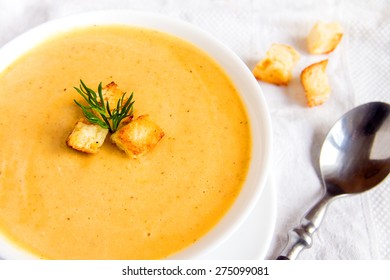 Cream soup with croutons and dill  on white napkin, horizontal close up