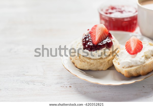 Cream teas with scones and clotted cream, raspberry\
jam, strawberries on the white table, copy space for text,\
selective focus