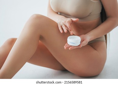 With cream. Woman in underwear with slim body type is posing in the studio.