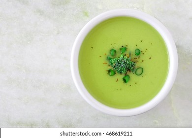 Creamy Broccoli Soup In A White Bowl, Overhead View On White Granite Background