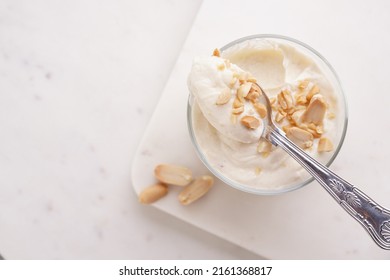 Creamy dairy yoghurt dessert with mascarpone, cream cheese and peanut butter in glasses on marble tray with a tea spoon - Powered by Shutterstock