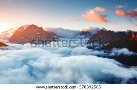 Creamy fog covered the famous glacier Marmolada in morning light. Picturesque and gorgeous scene. Location place Val di Fassa valley, passo Sella, Dolomiti, South Tyrol. Italy, Europe. Beauty world.