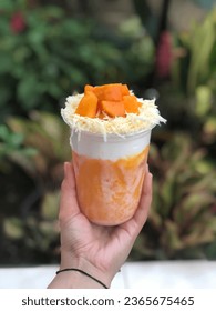 Creamy mango smoothie with whippedcream and cheese on top of it