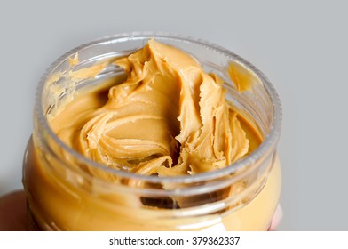Creamy peanut butter in a hand over grey