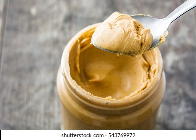 Creamy Peanut Butter And Spoon On Wooden Background
