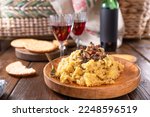 Creamy polenta with porcini mushrooms, bacon, served on a dark wooden background with a glass of red wine. Typical food of northern Italy, Trentino in the Alps 