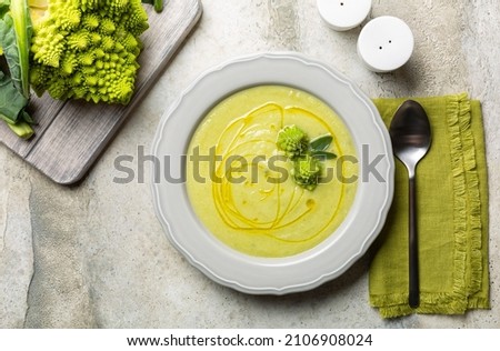 Creamy romanesco broccoli soup with olive oil. Vegan food. Fresh raw roman broccoli on background. Directly above.