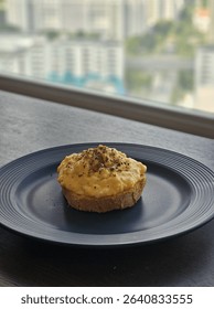 Creamy scrambled eggs served on toasted sourdough bread, topped with cracked black pepper and herbs. Simple and delicious breakfast dish, plated on a dark ceramic plate in natural light.