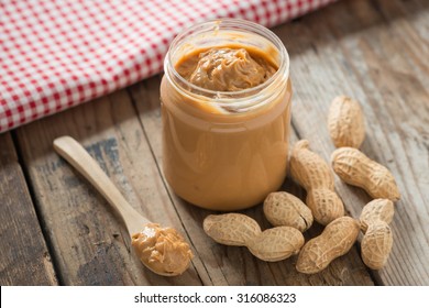 Creamy and smooth peanut butter in jar on wood table. Natural nutrition and organic food. Selective focus.