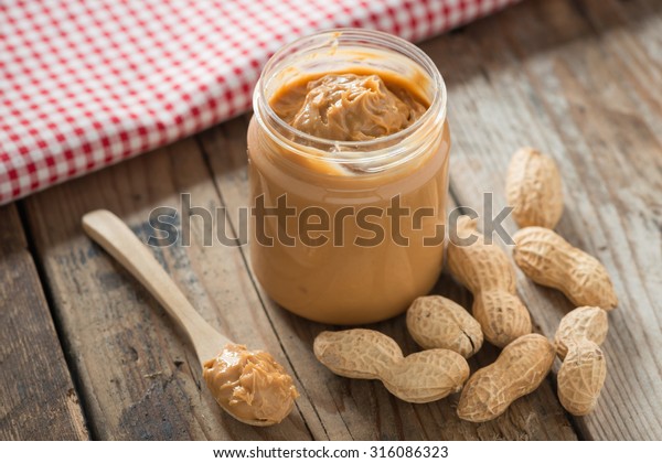 Creamy and smooth\
peanut butter in jar on wood table. Natural nutrition and organic\
food. Selective focus.