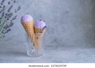 Creamy vegan lavender ice cream in a glass, stylized with flower buds. Summer seasonal cold sweet healthy dessert. on a gray background, space for text. High quality photo
