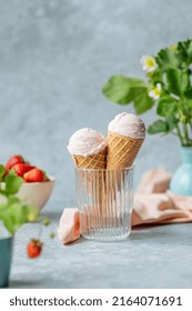 Creamy vegan strawberry Ice cream in the horn in a glass with strawberry flowers in a vase. Summer seasonal cold sweet healthy vegan dessert. High quality photo