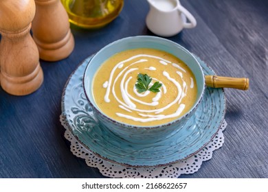 Creamy Zucchini, Yellow Squash Soup Decorated With Parsley And Cream Served In A Blue Bowl On Dark Wooden Table. Top View, Horizontal, Selective Focus