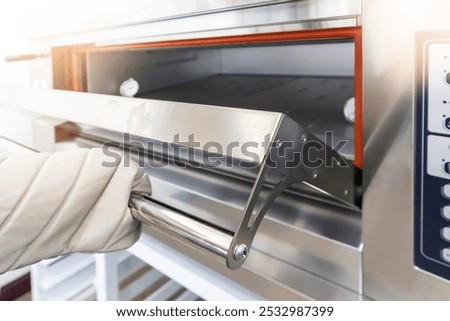 To create bread, a chef in heat-resistant gloves opens the oven.