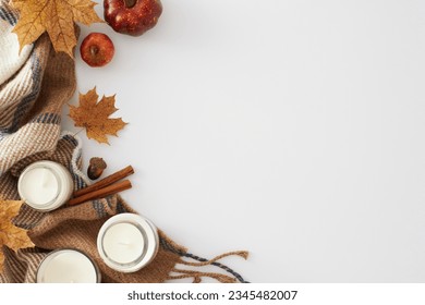 Create a captivating and autumn-themed setup. Top view shot of candles, warm blanket, pumpkins, acorn, cinnamon sticks, maple leaves on white background with empty space for advert or message - Shutterstock ID 2345482007