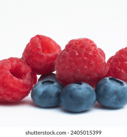 Create a picture of a berry for a product category on the site on a white background so that there are blueberries, raspberries, focus on raspberries