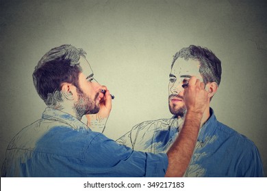 Create yourself concept. Good looking young man drawing a picture, sketch of himself on grey wall background. Human face expressions, creativity