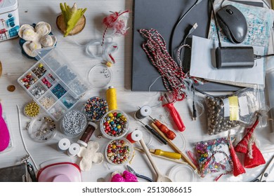 Creating Christmas ornaments. Handcraft artist workspace. Laptop, colorful beads, felt, tools, scissors, needles, thread spools, glue, containers, pliers, wire. Creative chaos concept. Flat lay. - Powered by Shutterstock