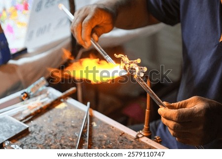 Creating glass art with hot torch and glassblowing pipe. The process of glass making, Glassblower shaping the red melted glass, A glass blower melting glas