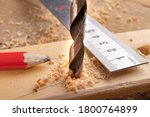 Creating holes with a metal drill in a piece of wood. Metal ruler for measuring the distance between the holes. Light background.