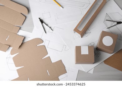 Creating packaging design. Drawings, boxes and stationery on light wooden table, flat lay - Powered by Shutterstock