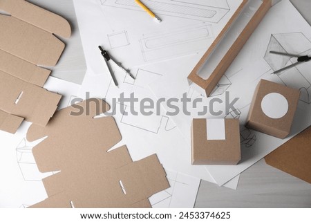 Creating packaging design. Drawings, boxes and stationery on light wooden table, flat lay