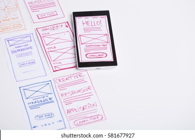 Creating responsive website for mobile devices, designer desk with sketches of mobile application layout