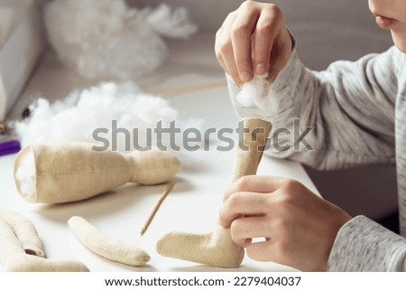 Creating soft stuffed toys with cotton filling. Close up of unrecognizable female tailor holding toy part, sewing and filling with cotton, making shape. Occupational opportunities for creative people