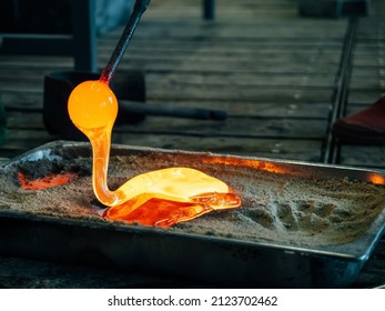 Creating traditional glass Art. Melting glass mould into sand form. Manual glass processing by the craftsmen inside a glass factory - Powered by Shutterstock