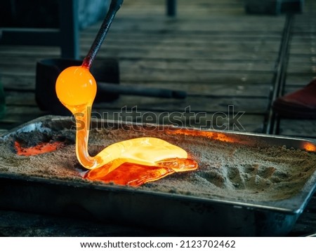 Creating traditional glass Art. Melting glass mould into sand form. Manual glass processing by the craftsmen inside a glass factory