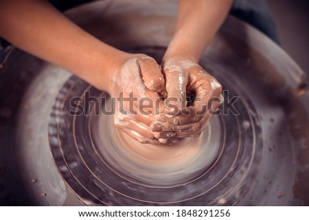 Creating vase of clay close-up. Master crock. The sculptor in the workshop makes a jug out of earthenware closeup. Twisted potter's wheel. Man hands making clay jug macro.