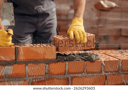 Creating the wall. Close up view of construction man that is working with bricks.