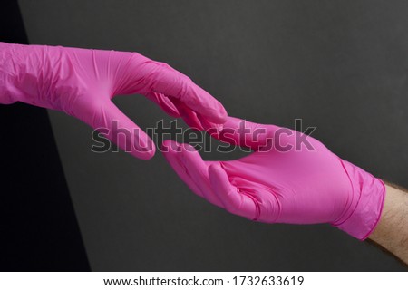 The creation of Adam in medicine gloves. Gesture from doctor's hands as metaphor of care, protect. Couple in pink gloves. Hands holding in sanitary gloves.