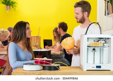 Creative 3D designers discussing over product at counter in printing studio