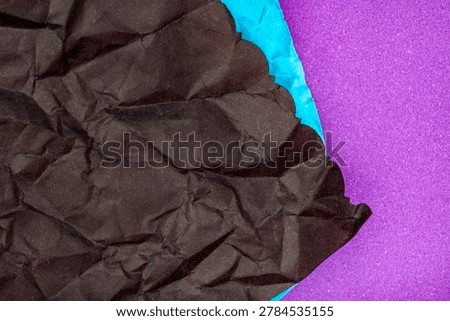 Creative abstract background featuring layered black crumpled paper against vibrant blue and purple textured colors. Bold modern backdrop suitable for graphic design, posters, banners and contemporary visual concepts.