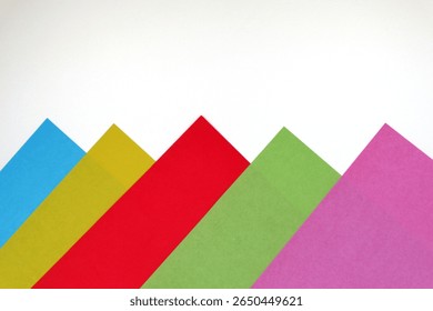 Creative abstract background made from overlapping pieces of colored paper in warm hues such as red, orange, and pink. Geometric shapes form a dynamic and modern composition.